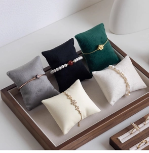 Detail of wooden tray with colorful velvet pillows displaying pearl bracelets and jewelry