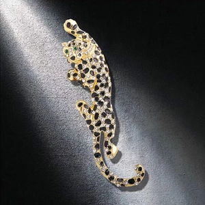 Sparkling leopard brooch in gold finish with crystals and black enamel on dark background