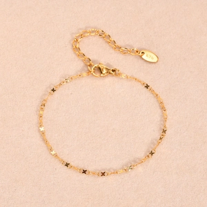 Macro detail of 18K gold bracelet featuring delicate butterfly links and K18 hallmark tag