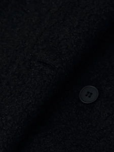 Detailed macro view of black wool fabric texture and four-hole button on the coat