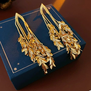Detailed view of elegant gold leaf tassel earrings on a premium blue jewelry box