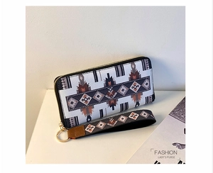 Detail of geometric pattern zipper wallet with golden hardware and matching wrist strap