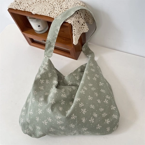 Detail of light green floral canvas tote bag featuring a rustic single shoulder strap design