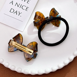 Set elastico con fiocco in acetato tartarugato e fermaglio dorato su un piatto di ceramica