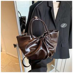 Detailed close-up of dark brown pleated cloud bag in shiny leather with soft texture