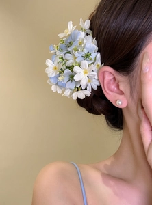 Detail shot of elegant blue and white flower cluster hair clip worn on model's head