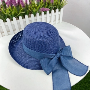 Detail of the navy blue straw hat featuring a wide ribbon and large side bow ornament