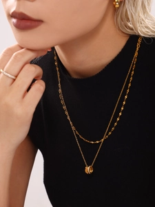 Close-up of a layered gold necklace featuring a sparkling triple-ring pendant on a model