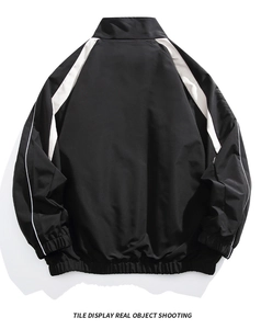 Detail of black and white windbreaker jacket with reflective stripes and elastic cuffs