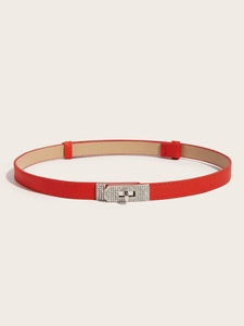 Macro detail of red litchi grain leather belt with silver diamond-encrusted buckle