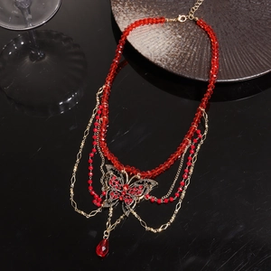Detail of red beaded necklace with rhinestone butterfly pendant and gold multi-layer chains