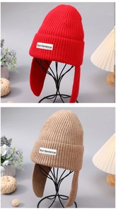 Close-up of thick knitted beanies in red and khaki with a branded woven label detail