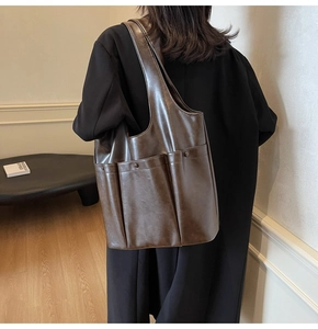 Model wearing a large dark brown PU leather tote bag with functional front pockets