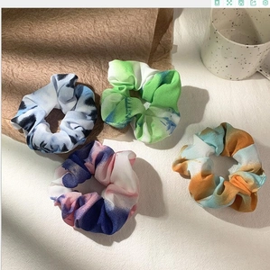 Tie-dye fabric scrunchies in vibrant colors displayed on a minimalist tabletop setting
