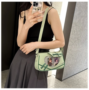 Detail of light green Ita bag featuring a heart-shaped clear window and punk rivet accents