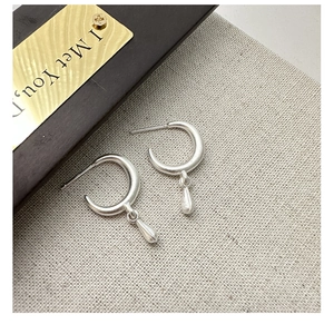 Detail of S925 sterling silver hoop earrings with frosted finish and teardrop pendant