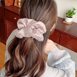 Pink shimmering fabric scrunchie shown from a back view on a model in a cozy home setting