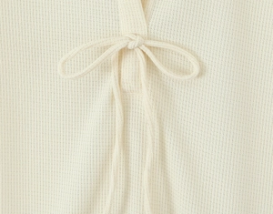 Detailansicht aus cremefarbenem Waffelstrick mit dekorativer Schleife am Polo-Kleid