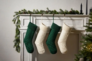 Detail of chunky cable knit Christmas stockings in dark green and ivory on fireplace