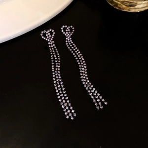 Close-up of silver heart earrings with sparkling rhinestone tassels on black background