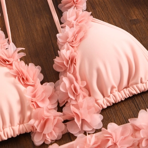 Detail of pink bikini top featuring handmade chiffon petal ruffles on smooth fabric