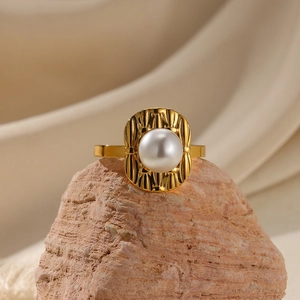 Detail of a vintage textured gold ring with a large pearl on a natural stone background