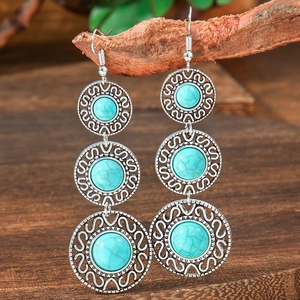 Detail of vintage bohemian drop earrings with turquoise stones hanging on a branch