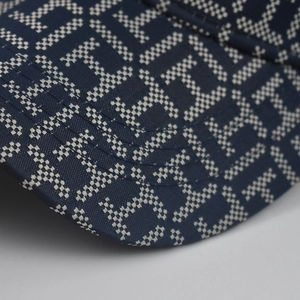 Close-up of navy blue baseball cap fabric with white pixelated H letter pattern detail