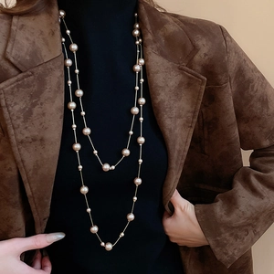 Elegant layered pearl necklace styling on a brown suit for a sophisticated winter look
