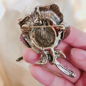 Vintage bronze rose brooch with purple rhinestones showing secure back pin clasp