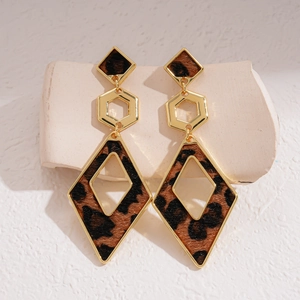 Close-up of leopard print geometric earrings with gold-tone hardware on white texture