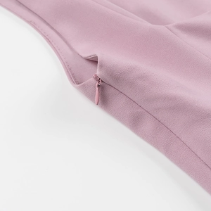 Gros plan d'une robe rose plissée montrant le détail de la fermeture éclair invisible