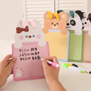 Detail view of a hand writing on a pink rabbit-shaped dry erase board with pastel pens