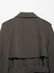 Detailed view of the water-resistant double-breasted trench coat back flap and waist belt