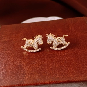 Macro view of gold rocking horse stud earrings with sparkling cubic zirconia pavé