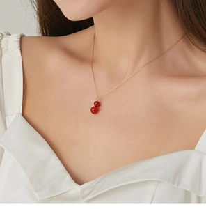 Detail of red agate gourd pendant necklace worn on neck with fine gold chain