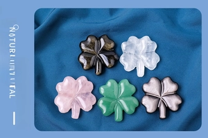 Detailed view of five assorted natural crystal four-leaf clovers on dark blue fabric