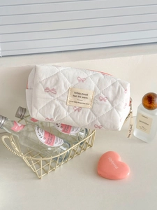 Trousse à maquillage matelassée blanche avec nœuds roses et ruban sur la fermeture éclair