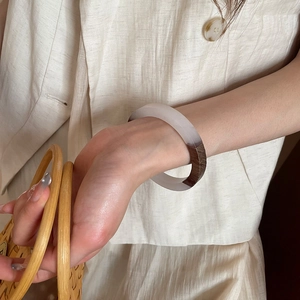Close-up of a circular bangle made of iridescent resin and wood texture on a female wrist