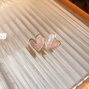Macro shot of small heart stud earrings with pink marble texture and gold metal frame