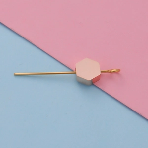 Detailed view of rose gold hexagon charm pendant with gold pin on colorful background