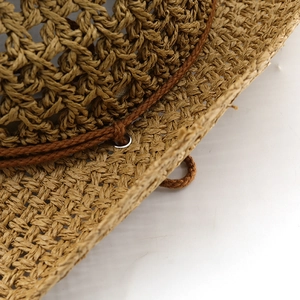 Detail of hand-woven straw hat showing breathable texture and brown rope with metal eyelet