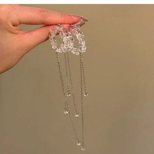 Close-up of irregular crystal geometric round earrings with long silver fringe tassels