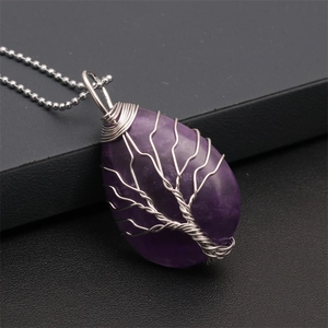 Detail view of purple crystal teardrop pendant with silver tree of life wire wrapping
