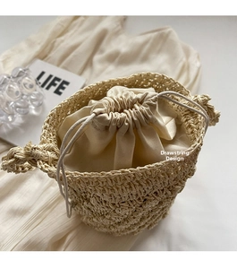 Detailed top view of handmade woven straw bucket bag with protective drawstring lining
