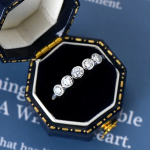 Macro shot of a silver five-stone moissanite ring in a premium blue hexagonal jewelry box