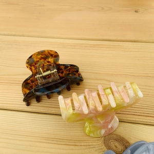 Detail view of floral tortoiseshell and pastel claw clips on a light wood background