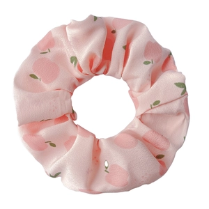 Detail of pink satin hair scrunchie with cute peach and leaf pattern on white background
