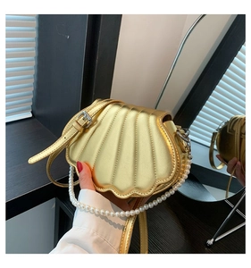 Nahaufnahme der goldenen Muschel-Handtasche mit Metalltextur und Perlen-Tragegriff