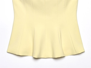 Detailed close-up of light yellow tube top hem with fine stitching and textured fabric